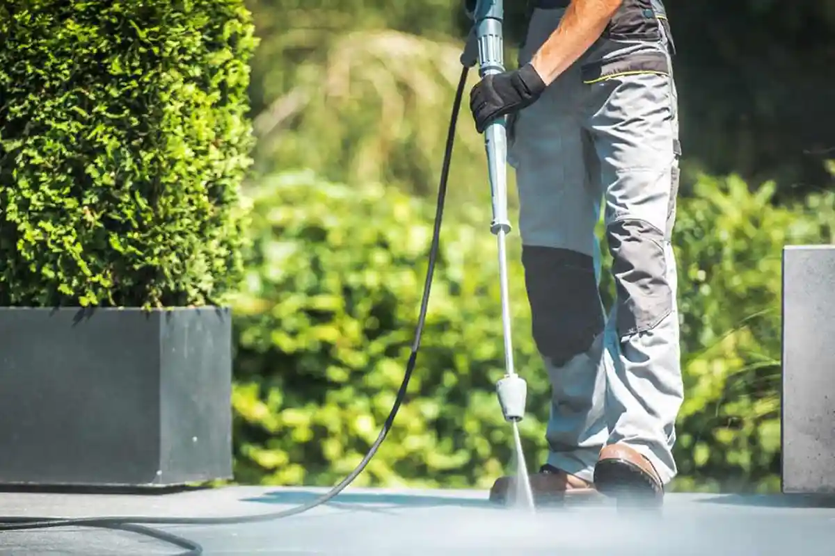 Contractor pressure washing a concrete patio, the kind of completed job a line-item invoice is built from