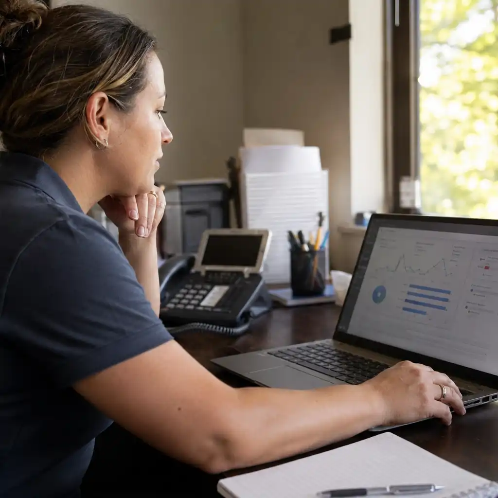 Service dispatcher reviewing connected appliance diagnostic data on a laptop before dispatch.